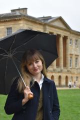 Photo of author Katie Kennedy standing in front of a historical building under an umbrella